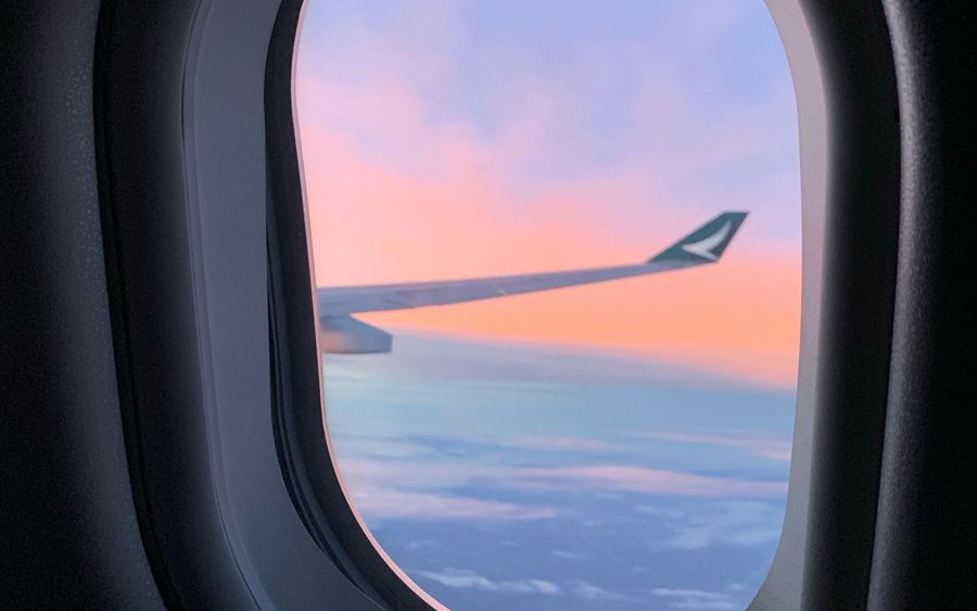 View of the wing and clouds from an aeroplane window at sunset
