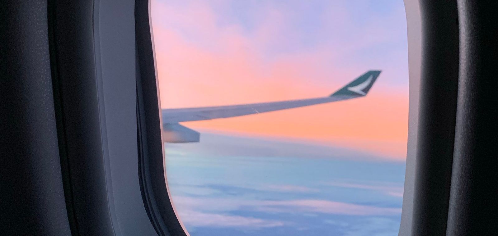 View of the wing and clouds from an aeroplane window at sunset